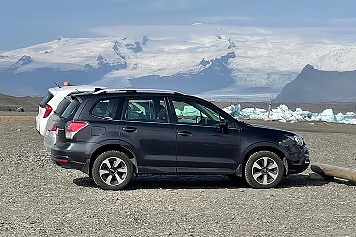 The rented Forester parked on a gravel lot with a glacier in the background.