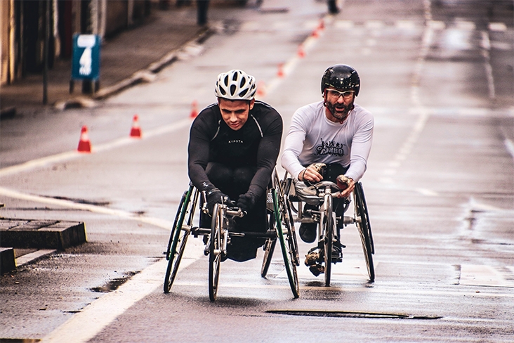 two men riding adaptive bikes down a road