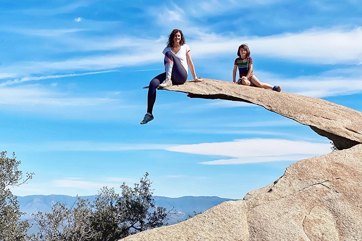  Maggie Downs and son, Everest Yasuda, pose atop Potato Chip Rock on the Mt. Woodson Trail near San Diego, California. Maggie has a leg dangling over the edge while Everest is seated with a leg stretched out on the rock formation.