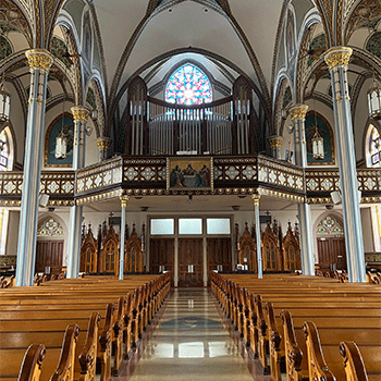 The interior of the Basilica of St. Francis Xavier in Dyersville, Iowa, featuring wooden pews, stained glass and a tall vaulted ceiling