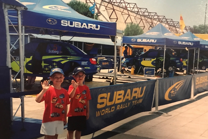 Panagiotis Argitis and his brother, Marcos, at the Acropolis Rally in 2005 standing in front of the lineup of Subaru tents and vehicles.