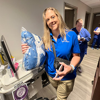 Janelle Stockwell is in a hospital setting holding a blanket that will be distributed to cancer patients.