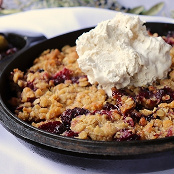 Fruit cobbler in a pan with ice cream on top.