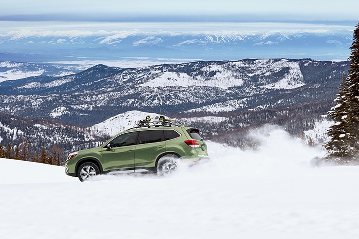 2021 Subaru Forester Touring in Jasper Green Metallic driving through snow in the mountains