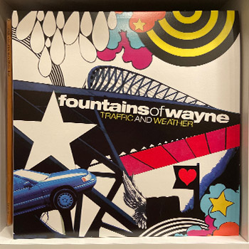 A photo of the author's album Traffic and Weather by Fountains of Wayne. The album cover is a collage style that's illustrated in black, white, blue, yellow, pink and orange images. A car, heart, star and bridge are among the images.