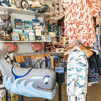 Interior view of Daytrip Jr. A large cartoonish whale is seen in the forefront, which has a seat for riding. In the background are books and racks of children's clothing.