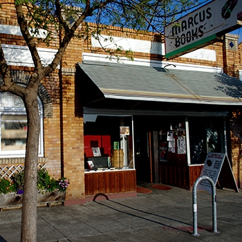 Exterior view of the Marcus Books brick building with a small tree in the foreground.