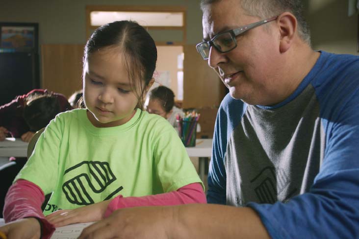 A man helps a young girl with schoolwork at the Boys & Girls Club.