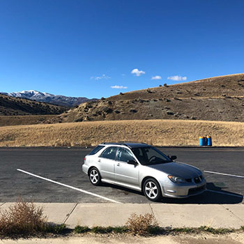 Julia Bainbridge’s 2006 silver Subaru Impreza parked in a lot with a desert and blue skies in the background.