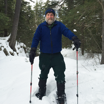 Smith showshoeing on a forest path covered in several inches of thick snow.