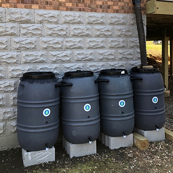 Black rain barrels ready to collect water along the back of Feldkamp’s house