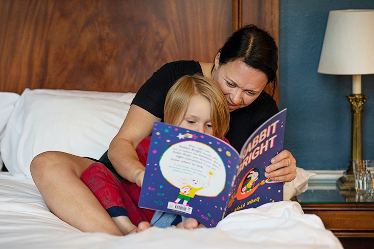 Woman sitting on a bed reading a bedtime story to her child