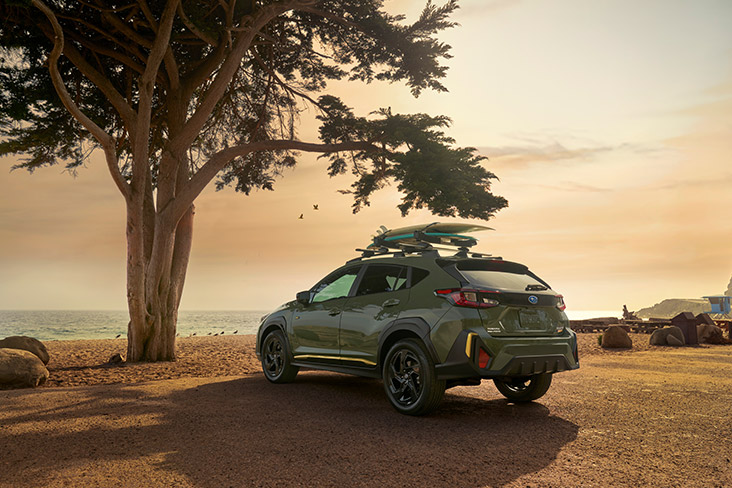 A rear 3/4 view of the Crosstrek at sunset by the beach