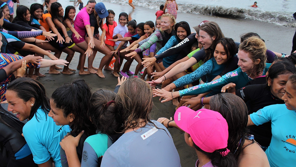 A group of students in wetsuits learning how to balance on a surfboard