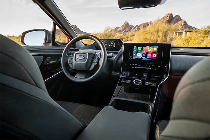An interior view of the 2023 Subaru Solterra, including the driver seat, steering wheel, gauge cluster and large touchscreen.