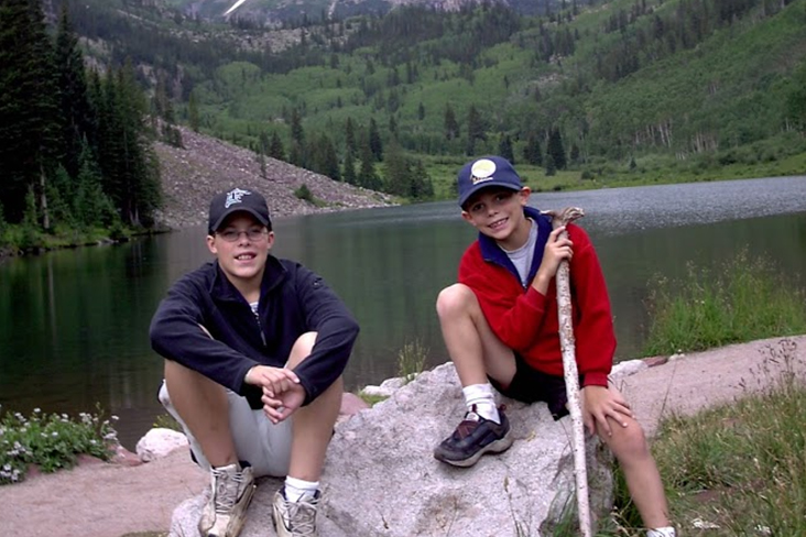 Two preteen boys posing near a lake