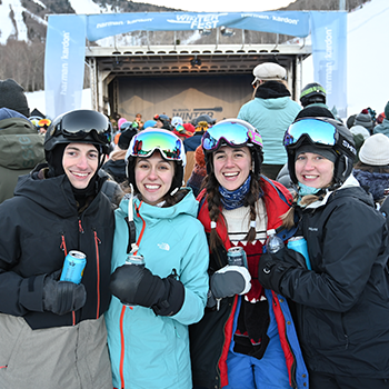 Four Subaru WinterFest participants smile at the camera in front of a stage.