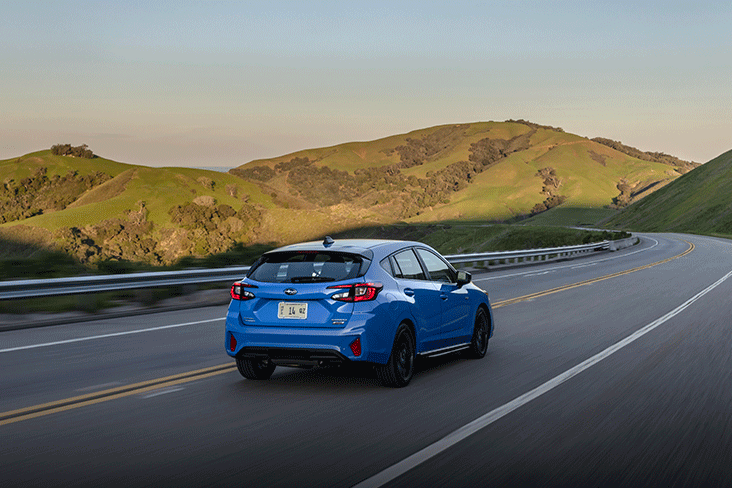 An action photo of the 2024 Subaru Impreza RS on the highway in Oasis Blue