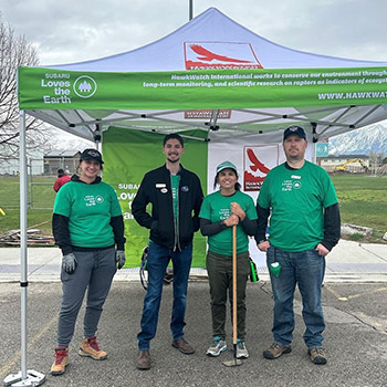 Caleb Calder stands with three other volunteers under a tent that says Subaru Loves the Earth for a cleanup event.