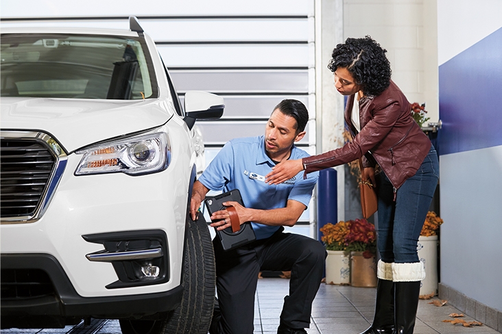 Subaru retailer technician assisting a customer with tire upkeep