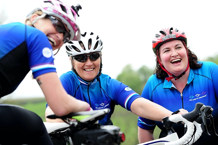 three women laughing on bikes