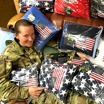 Apryl Williams poses with a shipment of pillows handmade by AaSP’s Director of Patriotism, Diane Casey. 