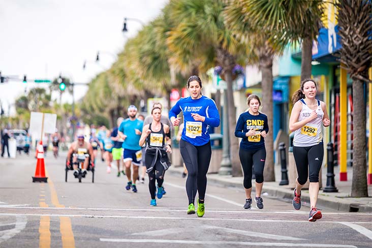 Race participants are seen coming down the road during the day in a race on the East Coast.