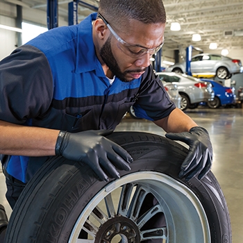Male Subaru University student installing a car tire