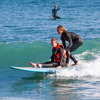 Surf instructor sharing surf board with student