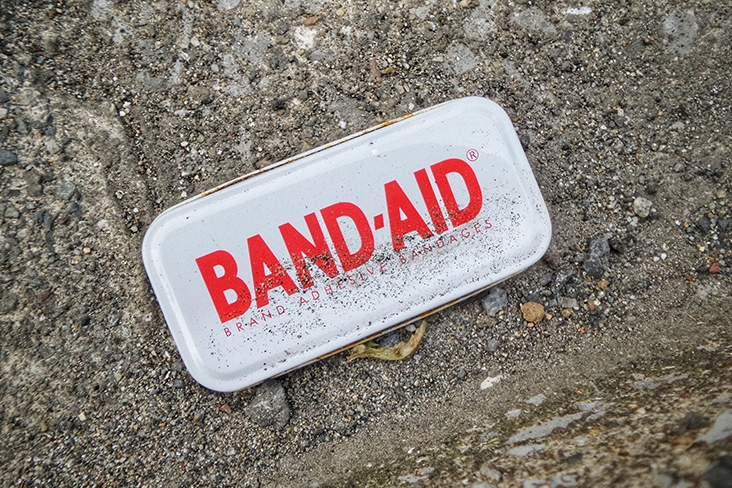 A Band-Aid case sitting on concrete