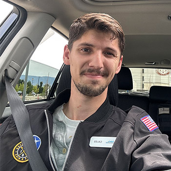 A medium shot of Caleb Calder seated in a vehicle, smiling.