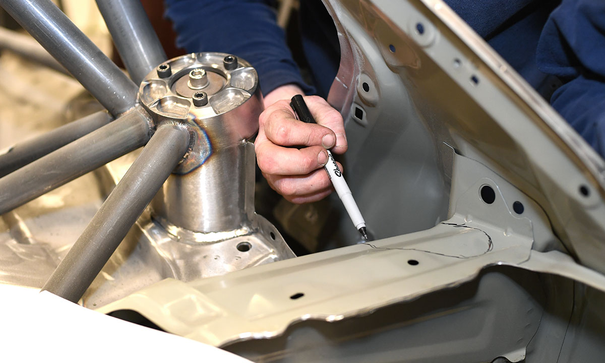 A technician uses precise measurements to create a custom-made roll cage.