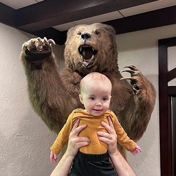 Kirby is being held up in front of a large taxidermied bear in the lobby of The Cheshire hotel in St. Louis, Missouri.