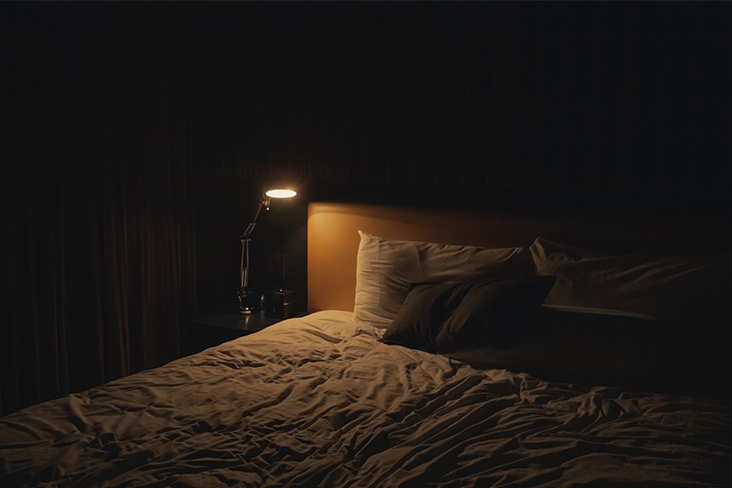 Darkly lit bedroom with a warm nightlight illuminating the nightstand and bed
