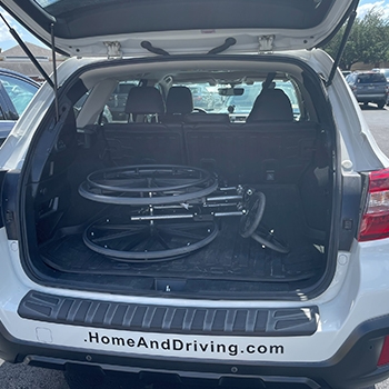 The trunk of the Subaru Outback is up and open, showing a wheelchair on its side.