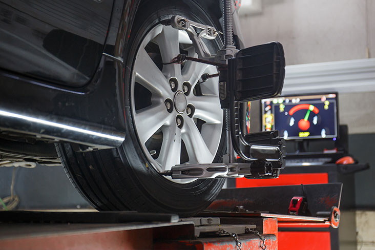 A vehicle in a retailer shop getting a wheel alignment.