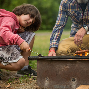 father and son cooking over a campfire