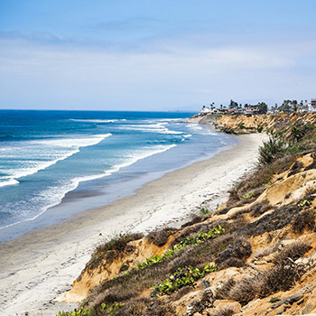 Gorgeous image of Carlsbad, California, with the ocean lapping against the shore and low bluffs.