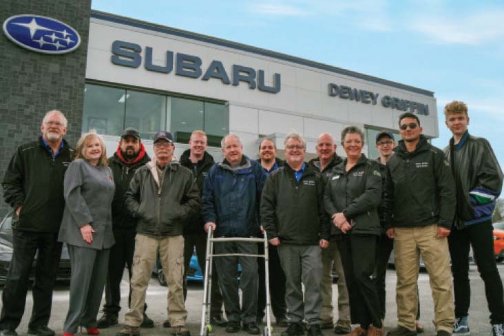 Employees at Dewey Griffin Subaru pose in front of the retailer’s building.