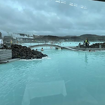 The Blue Lagoon geothermal spa with clouds in the sky and light blue water that has steam rising off the surface. 