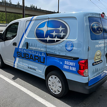 A three-quarter rear view of a van with a Peninsula Subaru wrap.