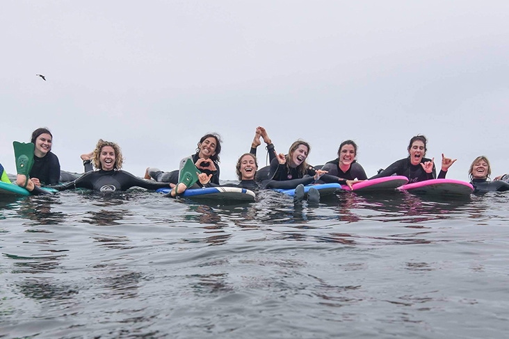 instructors and students posing for a group photo on surfboards in the water