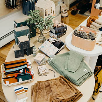 A table inside Kit Supply + Co. that's filled with items for sale, including clothing in pastel colors.