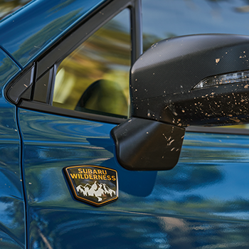Close-up of the front exterior mirror on the Subaru Forester Wilderness. Near the mirror is a Subaru Wilderness logo on the vehicle's door.
