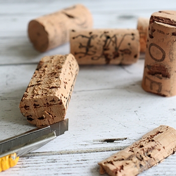 A closeup of corks. One has been divided, and a utility knife rests underneath it.