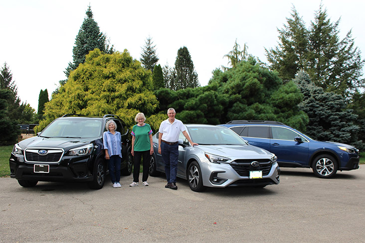  Three DuRide volunteers are standing next to their Subaru vehicles. From left to right are Kathy Loch Klein, Colleen Zelinsky and Mark Ressler.