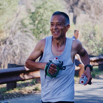 Ruperto Romero smiling as he runs a trail segment.