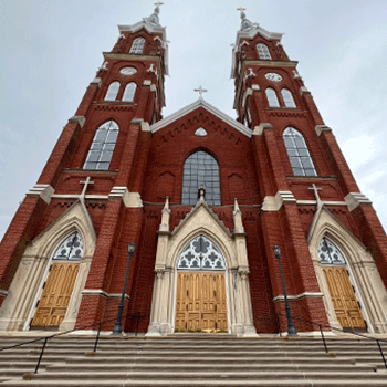 A photo showing the Basilica of St. Francis Xavier in Dyersville, Iowa, with a blue sky behind it.