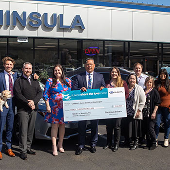 John Dionas with a group of employees holding an oversized check in front of the retailer.