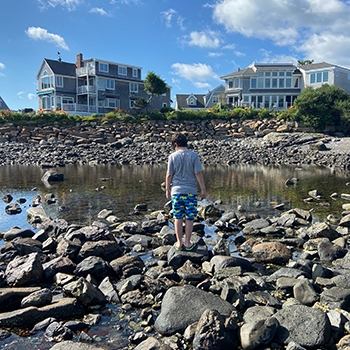 Young boy walking on the rocks on a beach in Maine